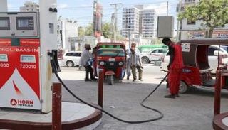 سائقو عربات التوك توك يدفعون إحدى المركبات إلى محطة وقود في مقديشو
