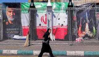 امرأة تسير أمام نماذج لصواريخ إيرانية في أحد ميادين طهران