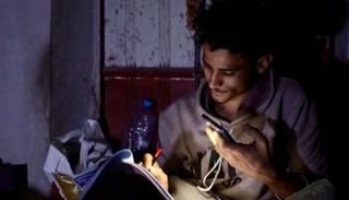 طالب يمني يذاكر دروسه على ضوء هاتفه في ظل انقطاع الكهرباء