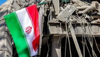 علم إيران أمام مبنى مدمر