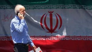 إيراني يمر أمام علم بلاده في ميدان بطهران