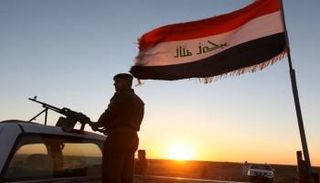 فرد أمن وفي الخلفية يظهر علم العراق - رويترز